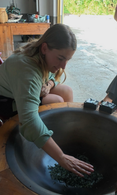 A guest shaping fresh leaves by hand at the pan