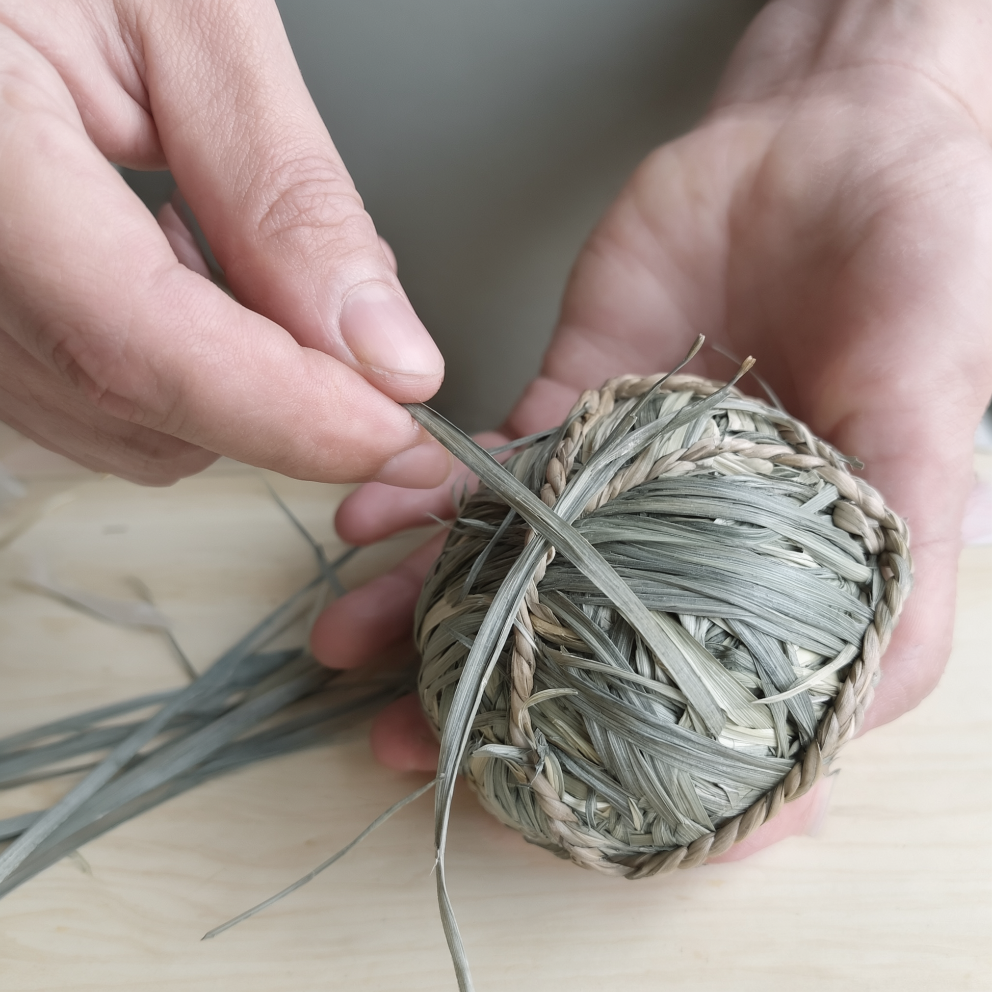 Village artisan hand-weaving a natural fiber chew ball in Wildbrook Village