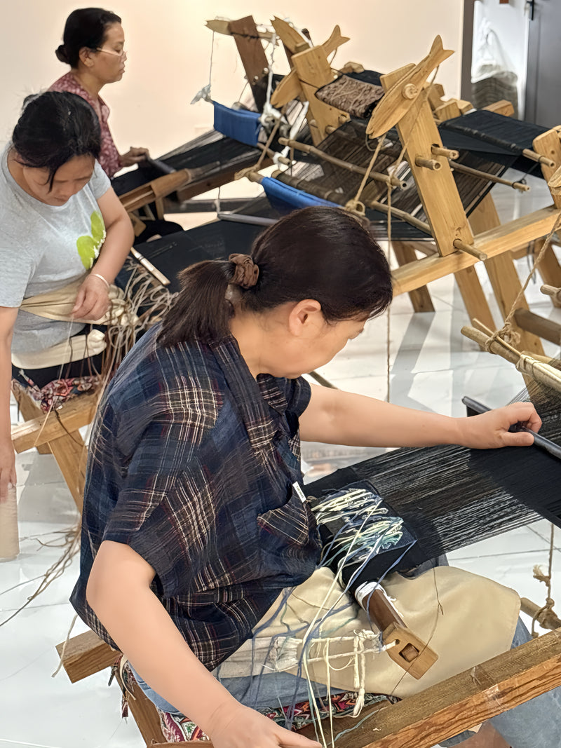 flowinversetea moms working on wooden looms in a workshop setting.